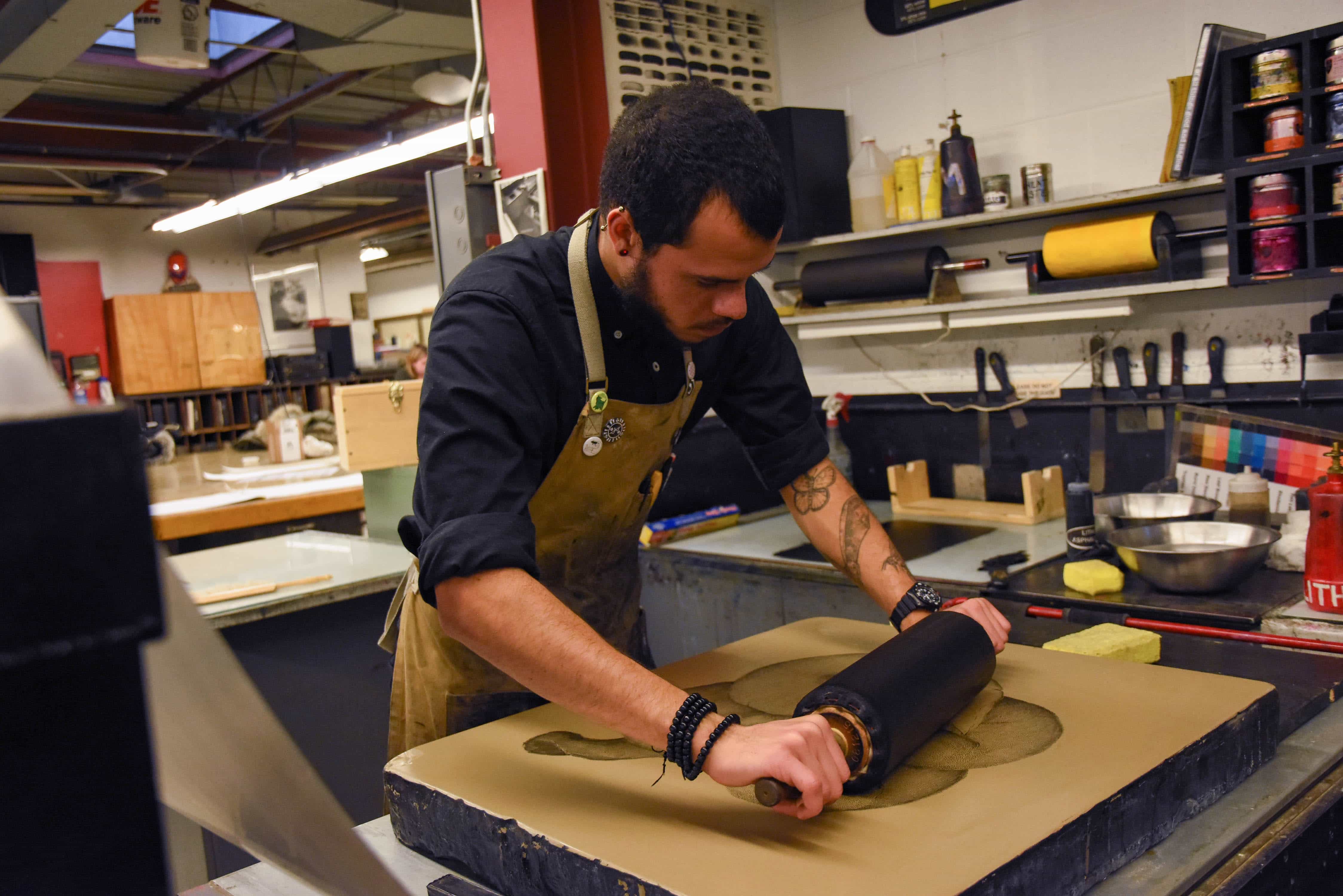 Nathan Taylor, a senior in studio arts, inks his stone in preparation to make a lithoraph at the Comstock Art Facility on November 14, 2018
