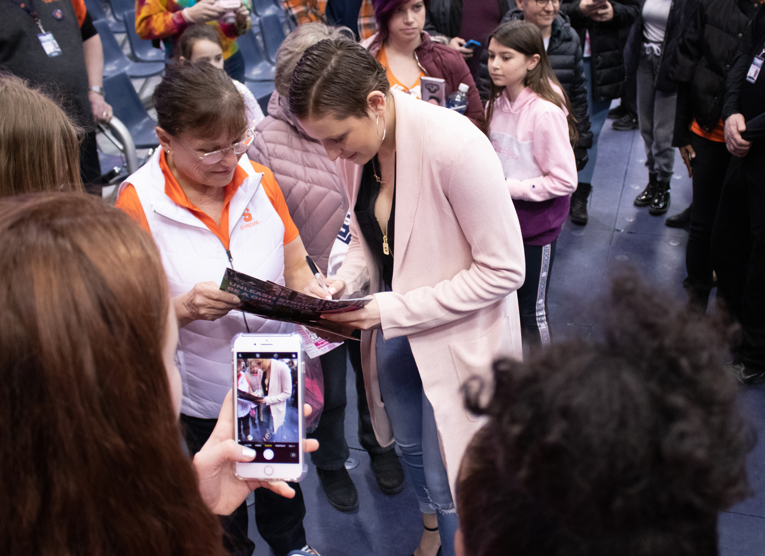 Syracuse University's guard, Tiana Mangakahia, signs a game pamphlet for a fan after a college basketball game against the University of Pittsburgh. Tiana Mangakahia is a breast cancer survivor and the Syracuse women's basketball team tried to raise awarness about the disease by encouraging fans and players to wear pink during Sunday's basketball game.