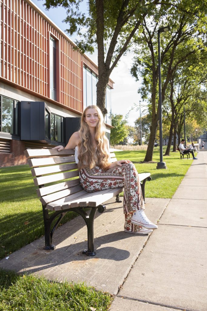 Chloe Meacham poses on a bench outside of the Schine Student Center at Syracuse University.