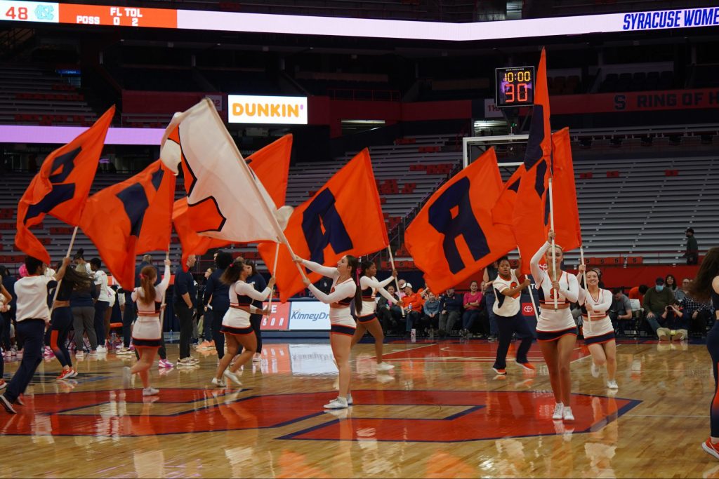 SU cheerleaders wave flags spelling out Syracuse during a women's basketball game on Feb. 9, 2023.