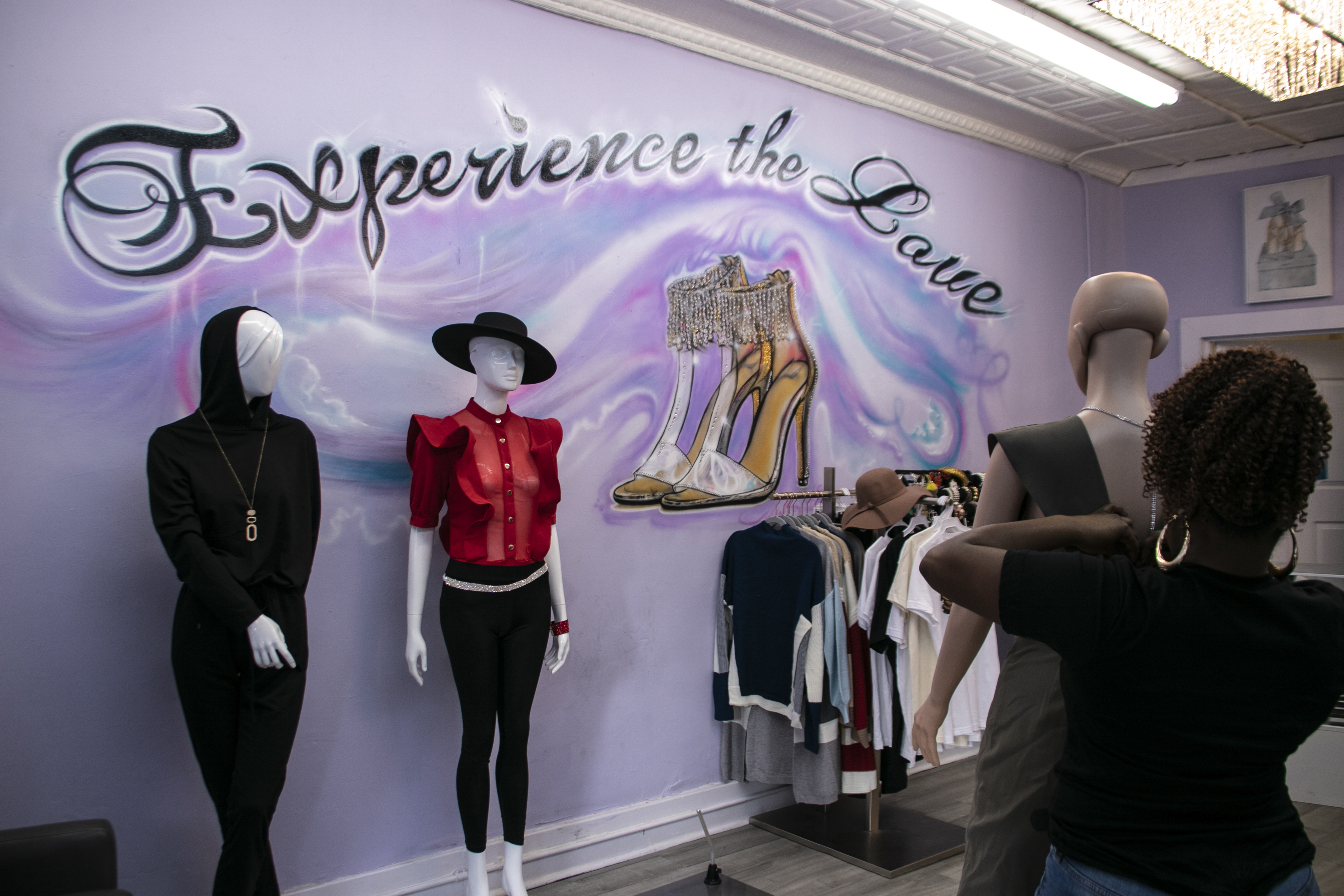 Tiara Love adjusts a jumpsuit on a mannequin in preparation for her customers. Love has been able to remain open since the pandemic started and now includes masks in the product she sells.