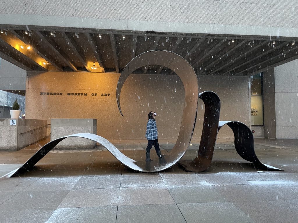 Fulmer stands inside a large metal sculpture outside the Everson as snow falls around him.