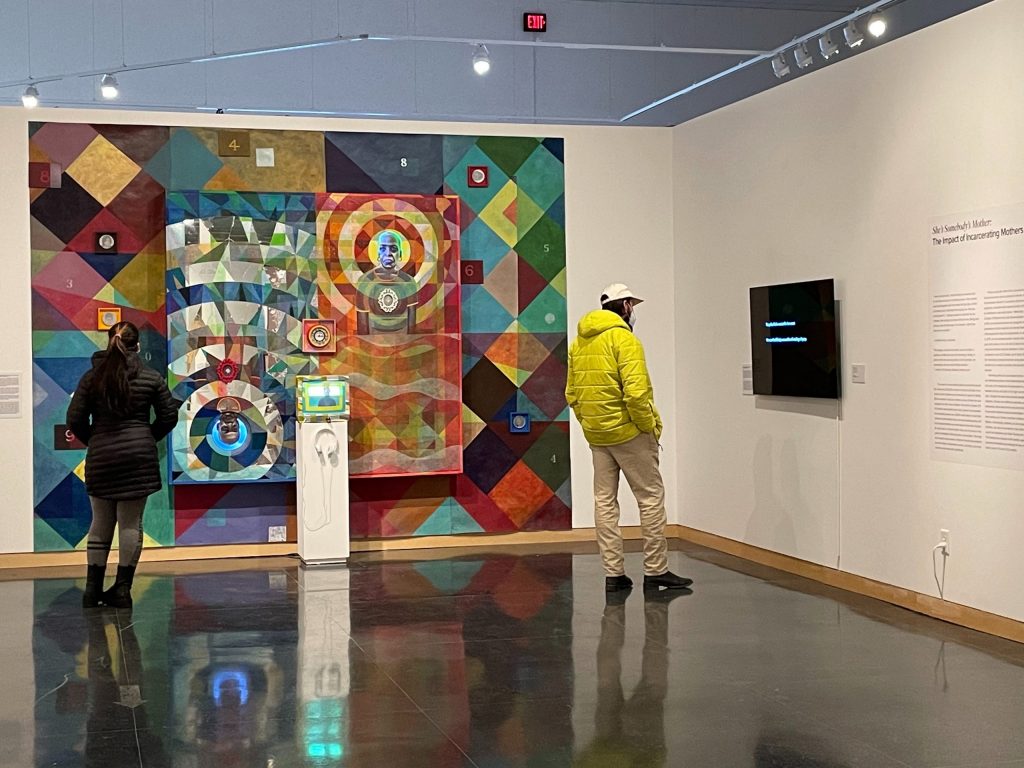 Museum goers in front of a piece by Carl Joe Williams