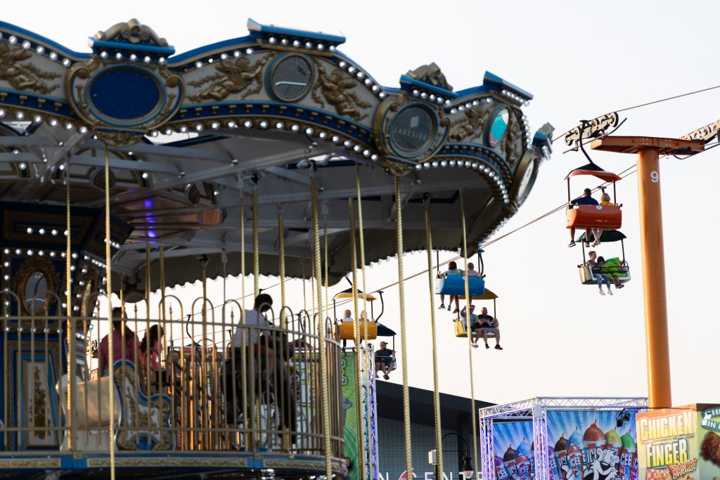 New York State Fair goers ride on the gondola and watch others from the Merry-Go-Round.