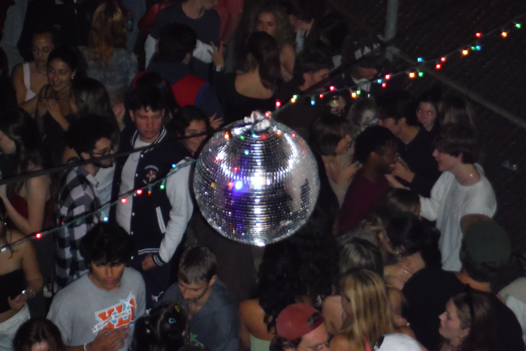 Disco ball hanging in the center of the outdoor venue Cage surrounded by students