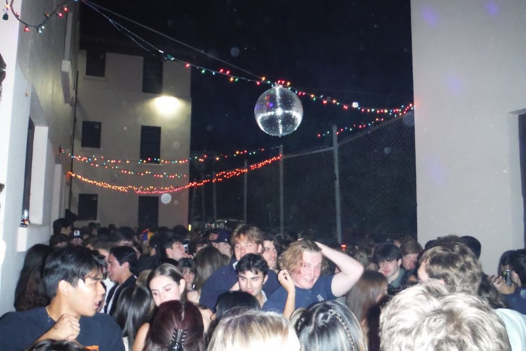 Crowd of students outside under disco ball and lights at the Cage concert venue