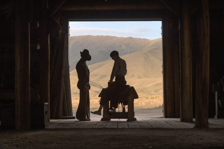 BENEDICT CUMBERBATCH as PHIL BURBANK, KODI SMIT-McPHEE as PETER stand in a barn in THE POWER OF THE DOG.