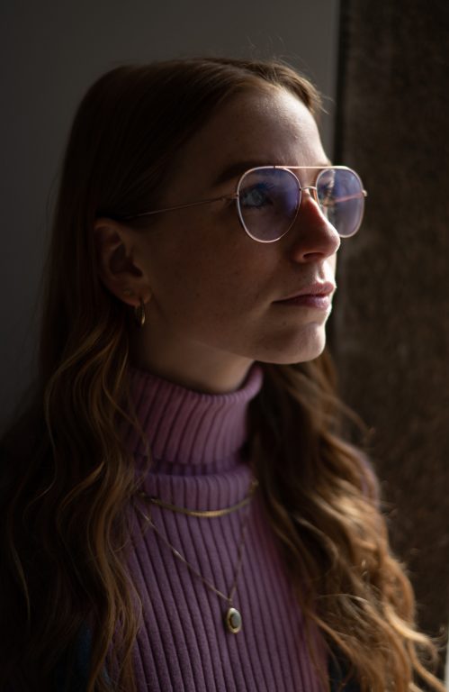 Abigail Tick wears glasses and a pink turtleneck while posing for a portrait
