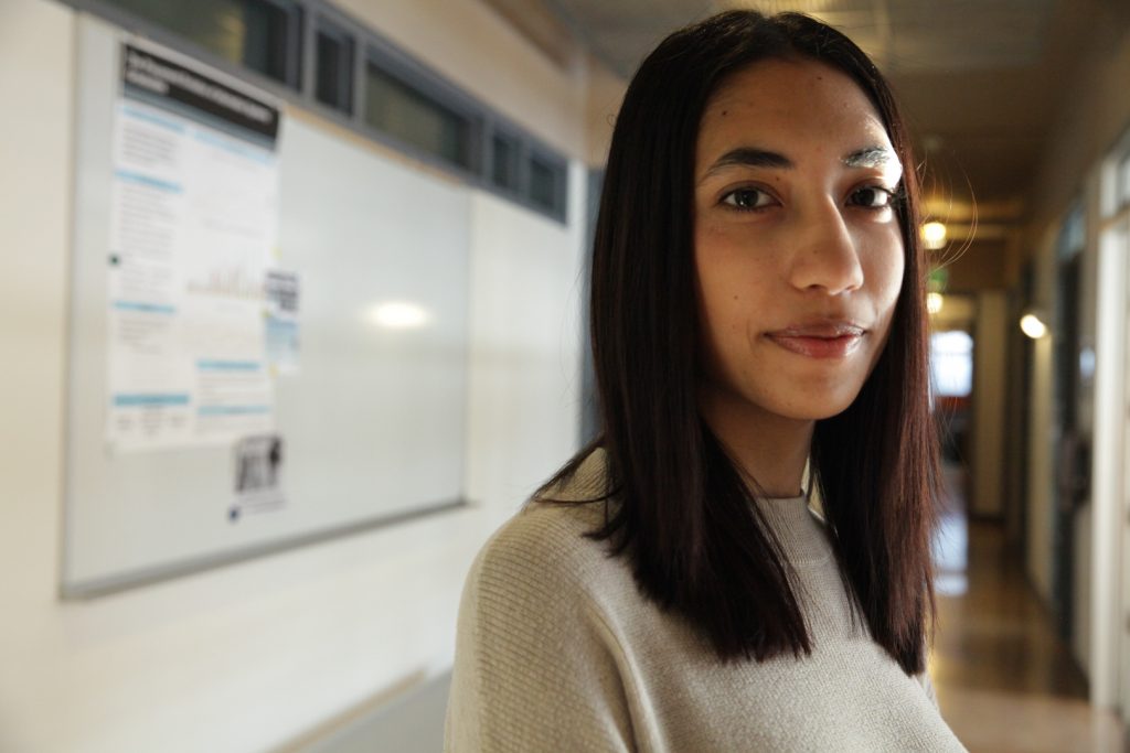 Mona Pudasaini looks into the camera standing in a hallway in the iSchool