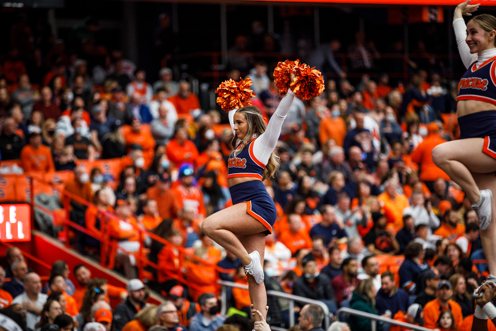 Cheerleaders held up in the air waving to the crowd.