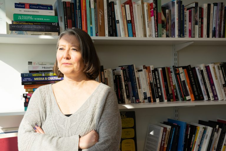 Dr. Anne Osborne stands in front of her book shelf for a portrait