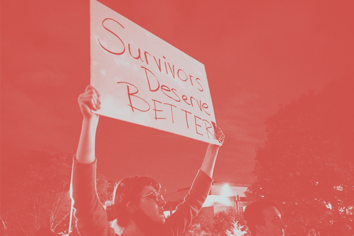 A protestor holds a sign that reads Survivors deserve better