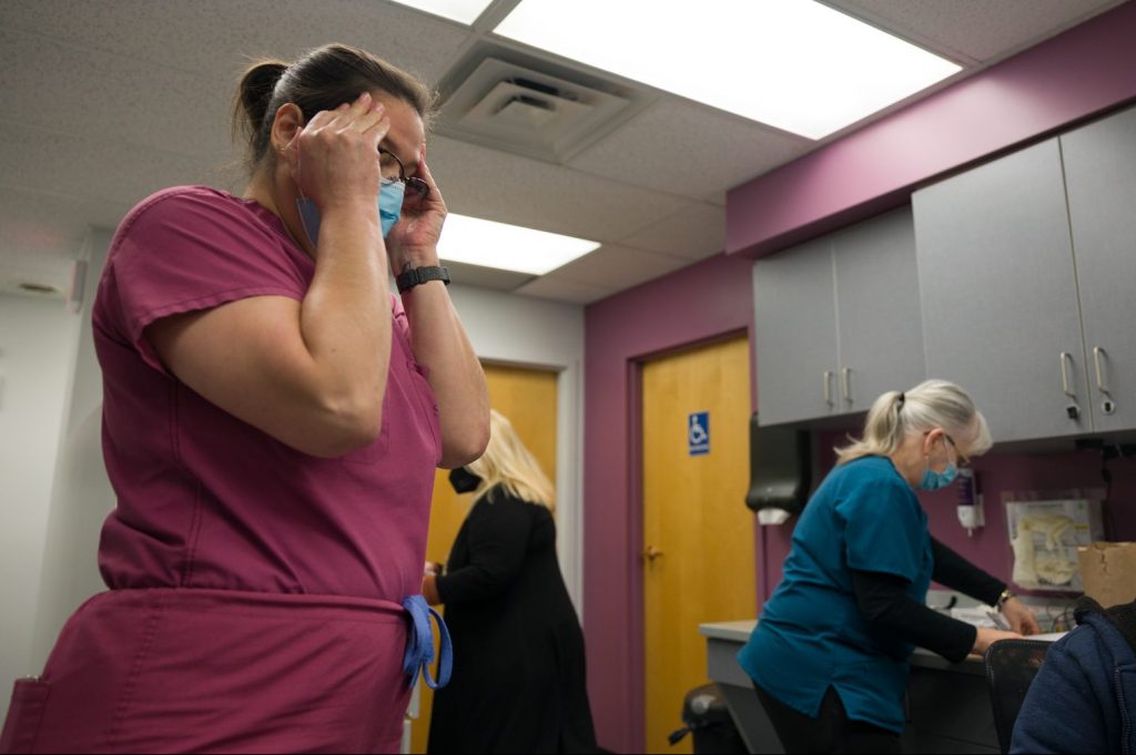 Renee Mestad has her fingers at her temples while working in the clinic