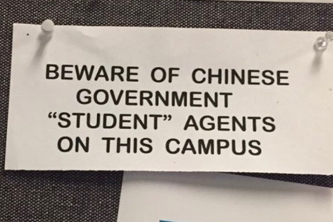 A note on a bulletin board reads "beware of Chinese government 'student' agents on this campus."