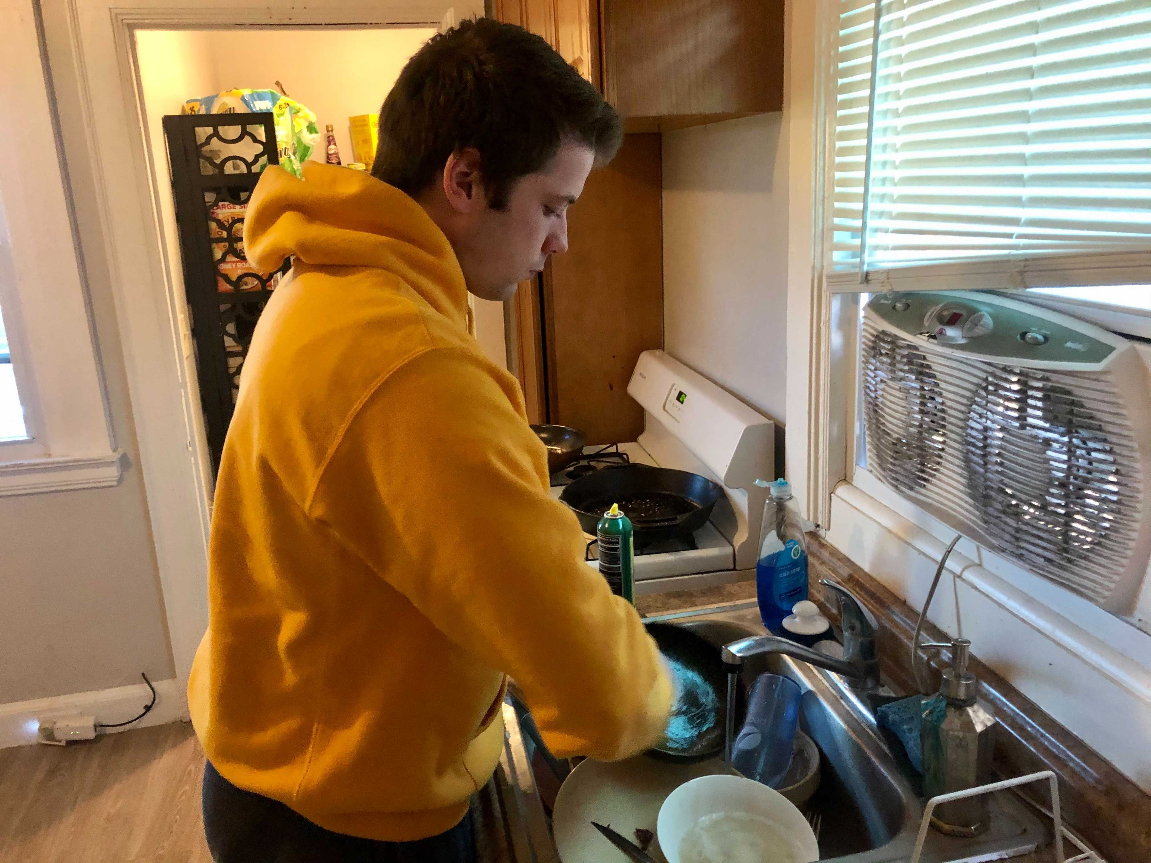 Michael Bottazzi cleans his dirty dishes in the sink.