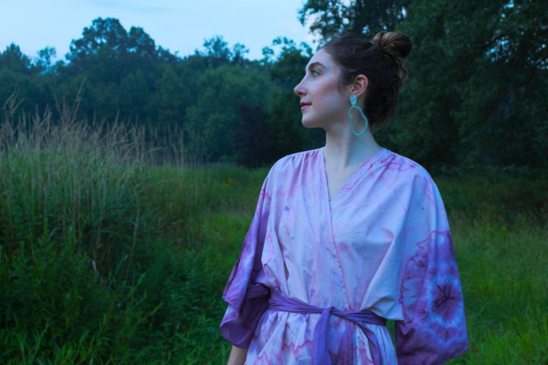 A model in a green field wears a kimono designed and made by Isabelle Collins. She used recycled cotton sheets and then tie-dyed them using beets and blueberries.