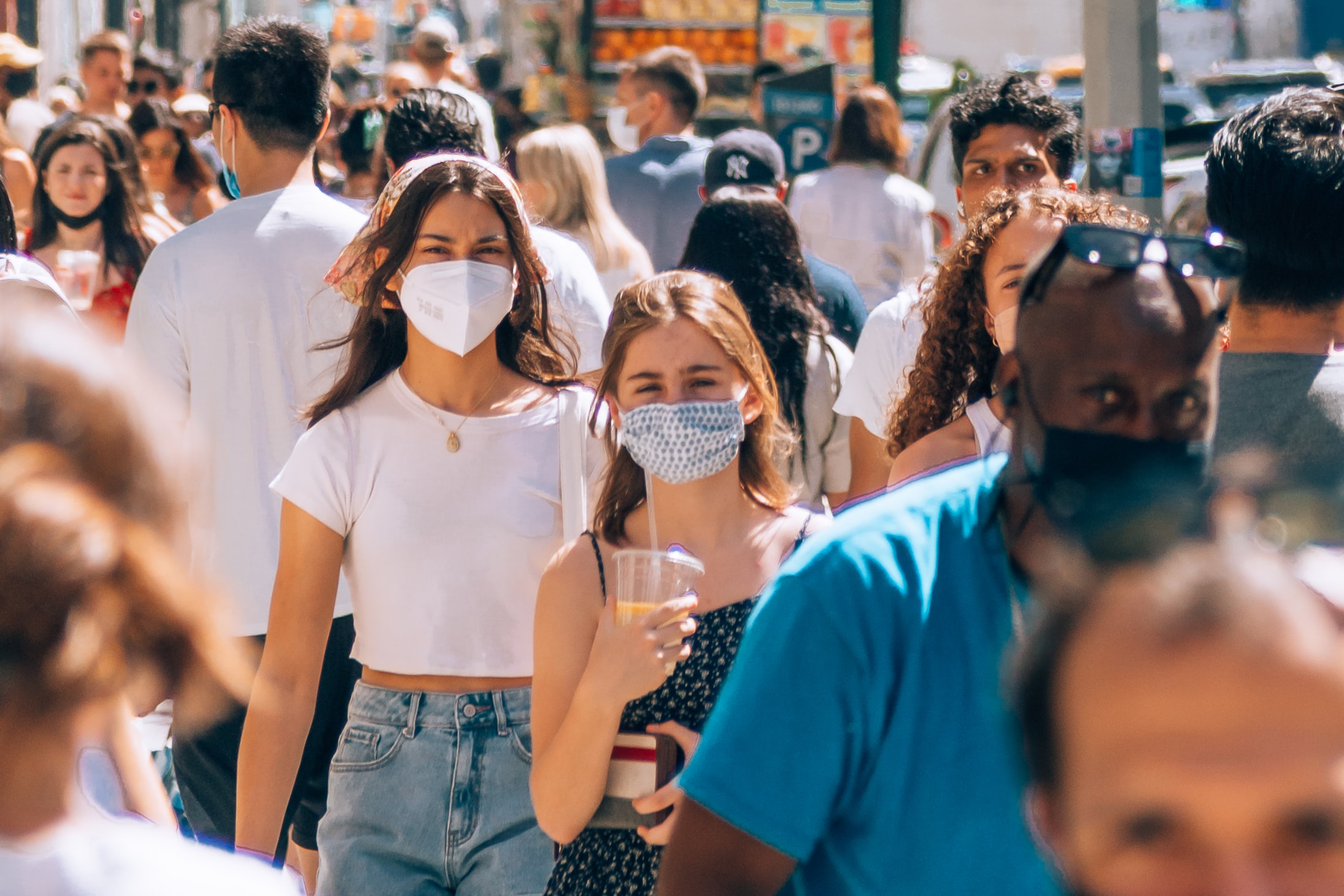 People walk with masks on in a crowded street