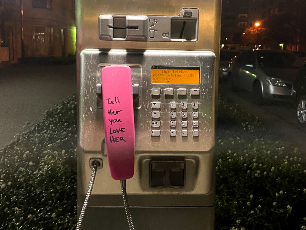 Pink payphone that reads 