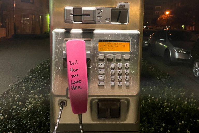 Pink payphone that reads "Tell Her You Love Her"