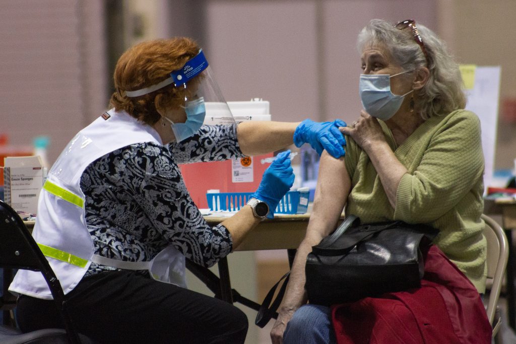 A woman receives a dose of the COVID-19 vaccine from a volunteer nurse.