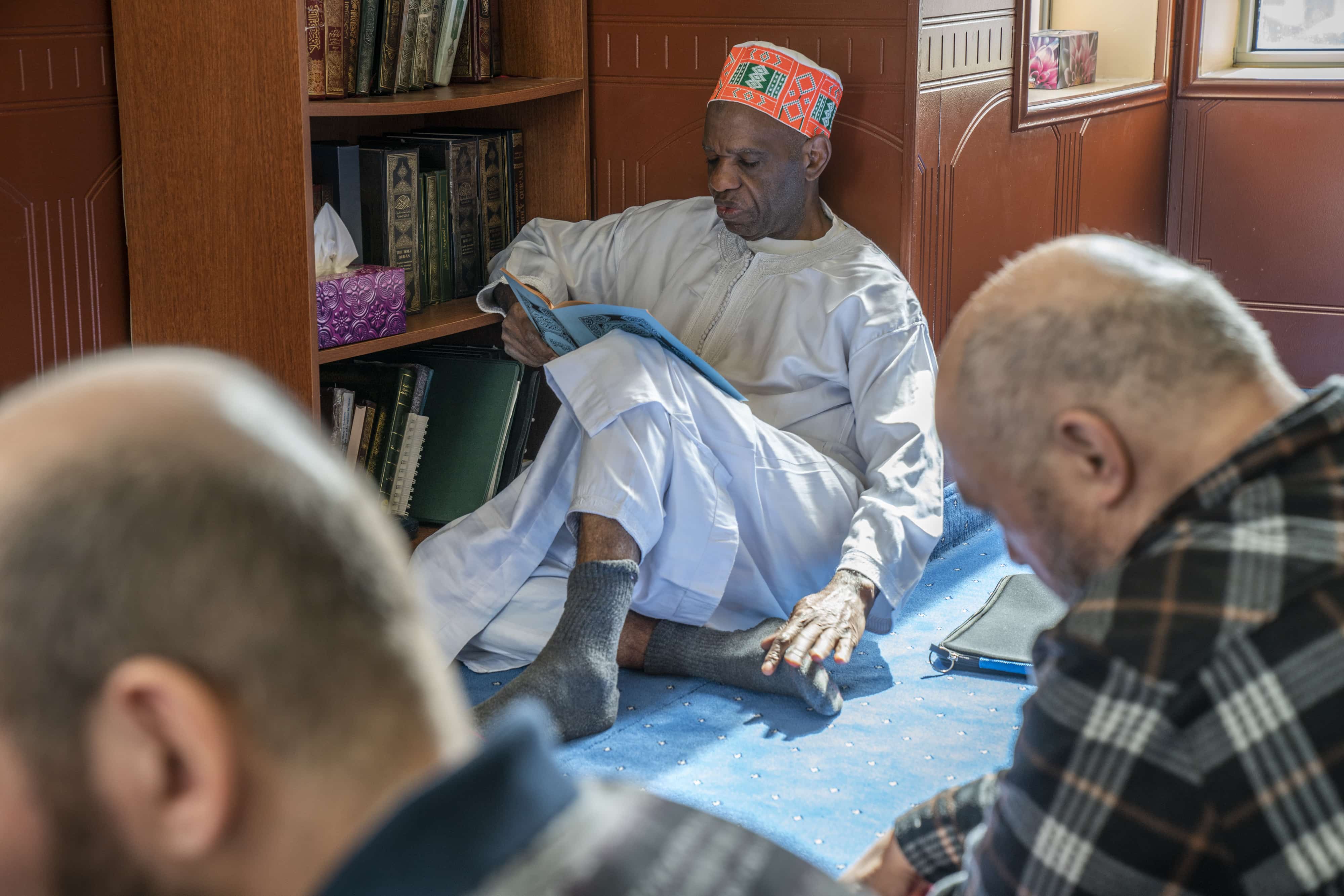 A man studies the Quran amidst the congregation. The Quran is the main holy scripture of Islam.