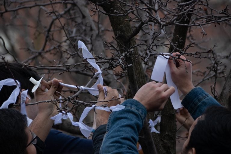 Community members tie white ribbons around the trees in front of Hendricks Chapel on Tuesday, March 19, 2019, in memory of those who where lost in the mass shootings in Christchurch, New Zealand.