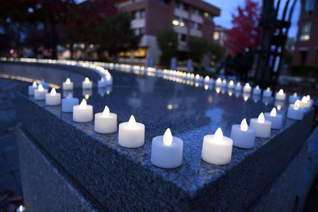 Lit electric tea lights sit on a gray stone bench.