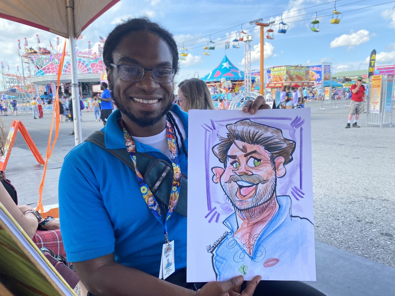 Caricature artist Jarrett Greene poses with one of his portraits at the New York State Fair.