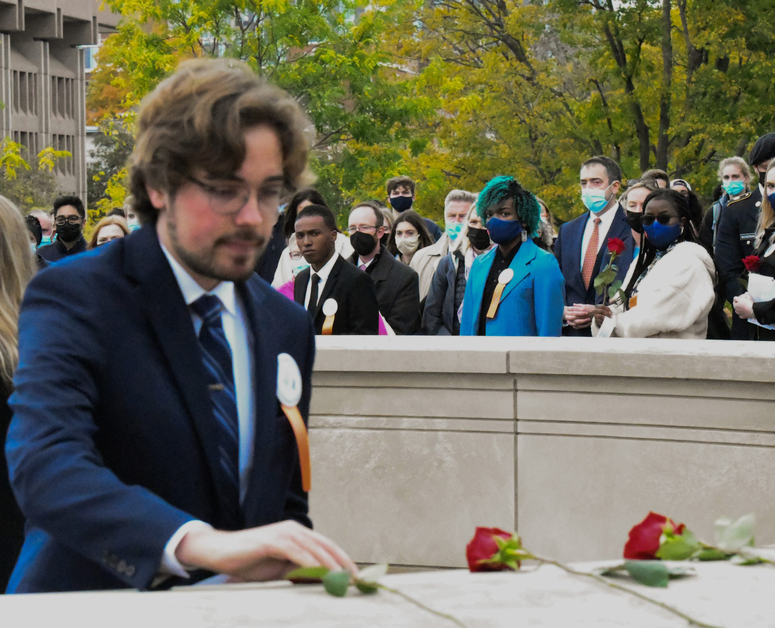 Morgan Eaton sets a rose down during the 2021 Remembrance Week Rose-Laying ceremony. Fellow Remembrance scholars wait to present their own stories about the 35 students whose lives were lost during Pan Am flight 103. (Rebecca Lan/The Newshouse).