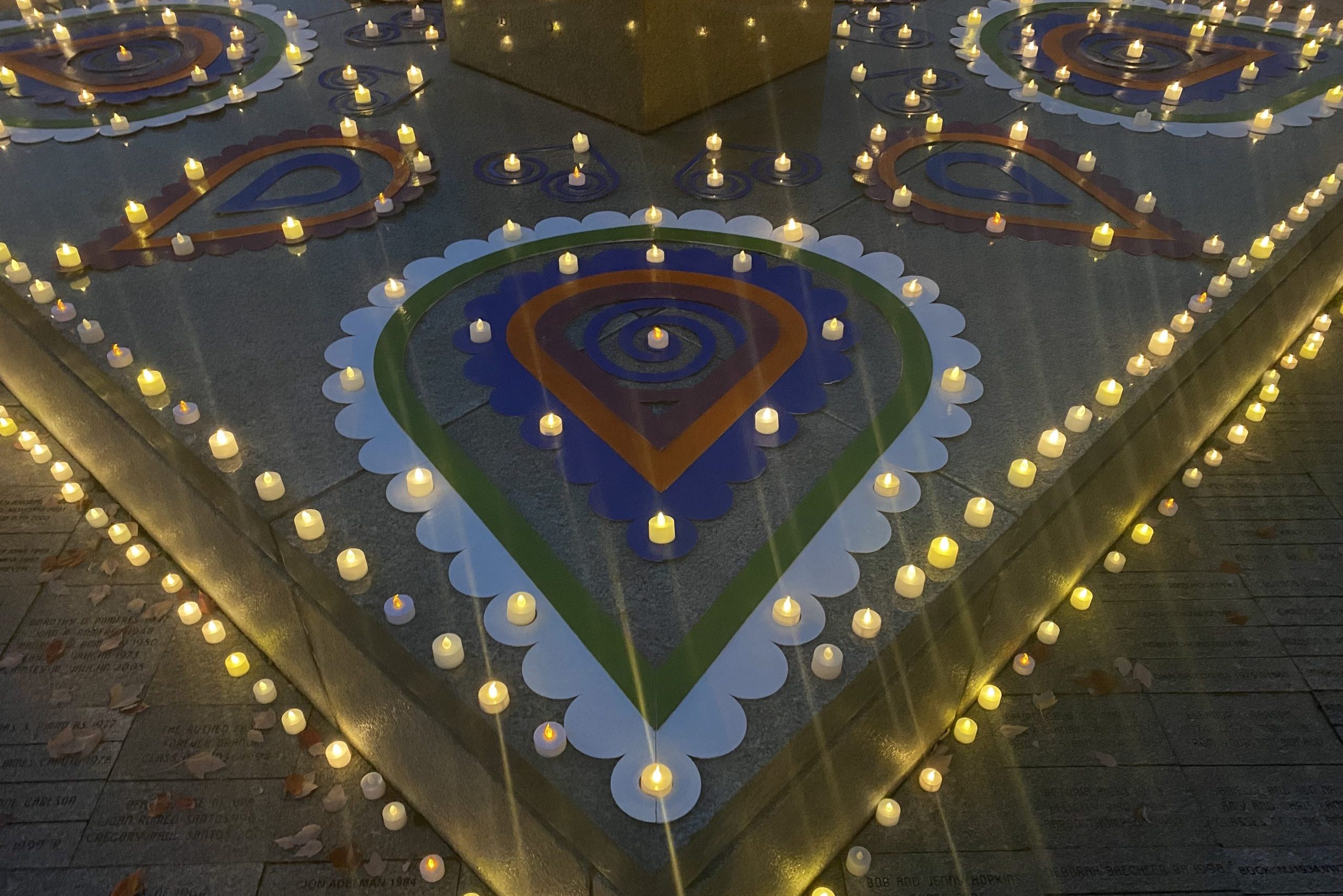 Colorful rangoli designs are surrounded by artificial candles.