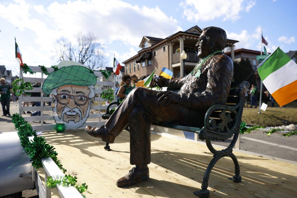 A new bench and statue commemorating the late owner of Coleman's Authentic Irish Pub and creator of Green Beer Sunday, Peter Coleman, sits on a parade trailer with a small Ukrainian flag in its hand on Tompkins Street.