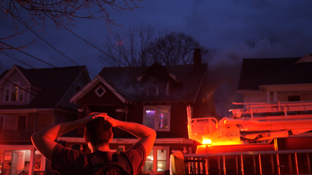 A University Neighborhood resident looks on as firefighters respond to a fire at house on Ackerman Avenue on April 10, 2022.