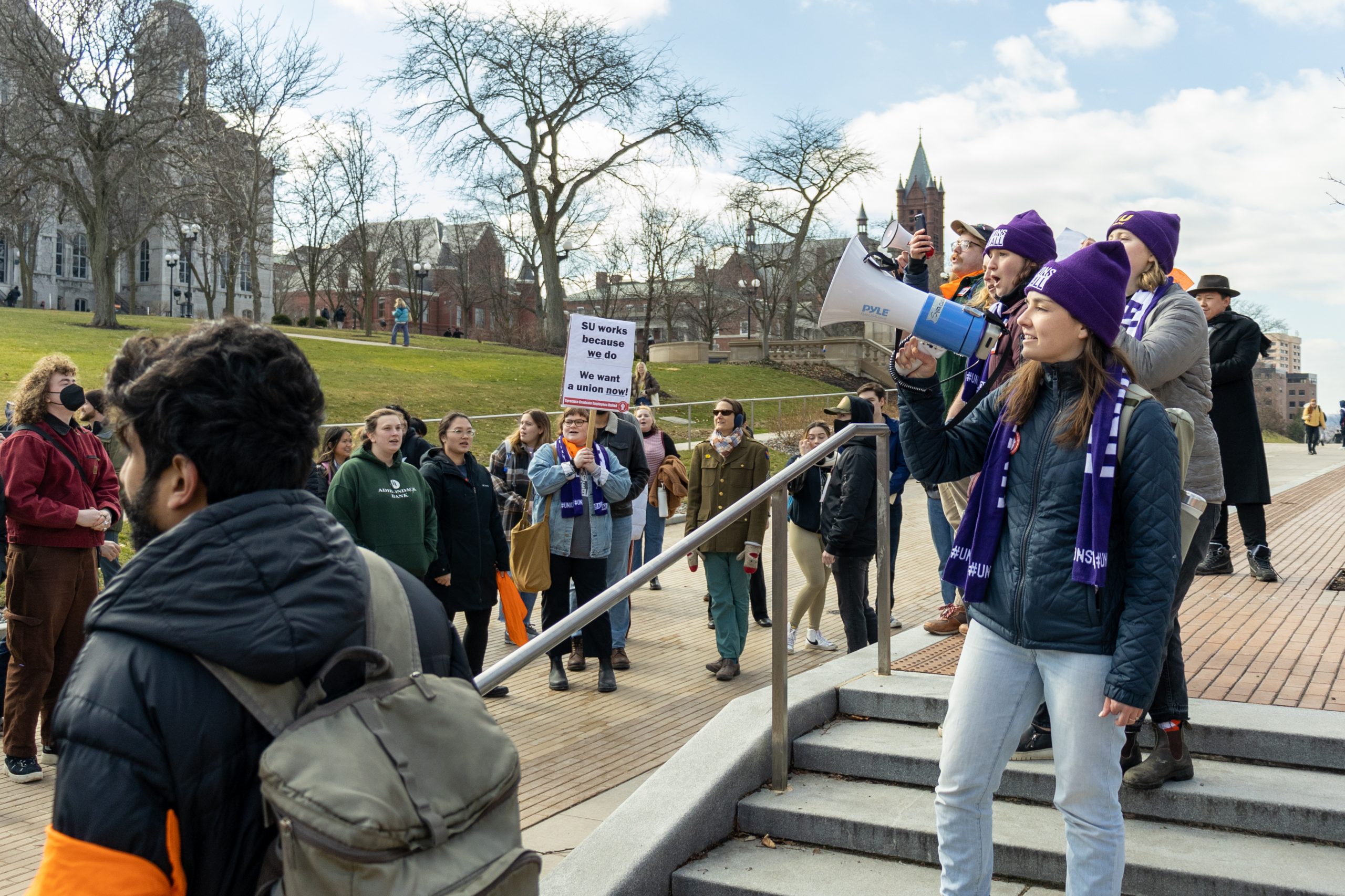 The Syracuse Graduate Employees Union gathered fellow students, supporting faculty and staff, as well as regular observers at the steps of Carnegie Library as they advocated for the University to recognize the union and accept the union's demands. The group then marched to the student center and onwards to the administration building where leaders would meet with the Provost.