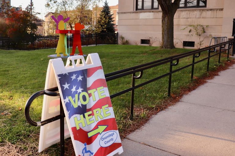"Vote Here" sign next to the sidewalk leading to the entrance of Beauchamp Public Library in Onondaga County
