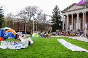 Protestors gather on the steps of Henricks Chapel to hear Mx. Yaffa speak as others continue to make signs and set up tents in the SU quad encampment on April 30, 2024.