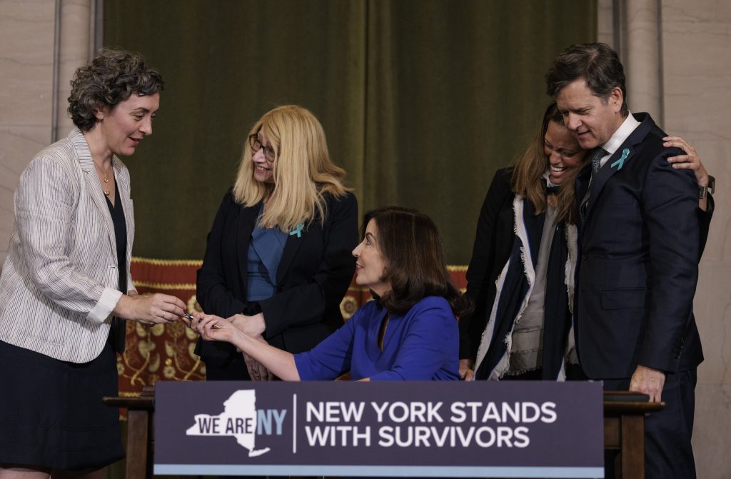Governor Kathy Hochul signs the Adult Survivors Act in the Red Room at the State Capitol with survivor and advocate Marissa Hoechstetter.