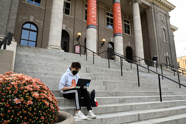 Student works online on the steps of Carnegie Hall.