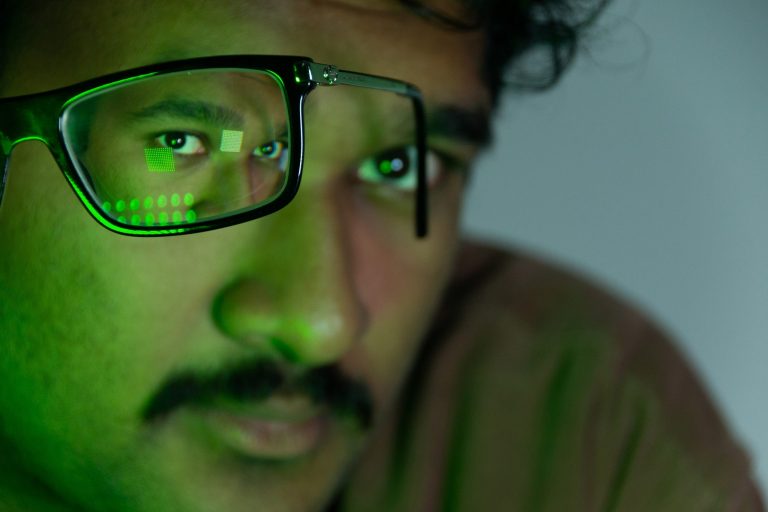 On October 23, Surya Vaidy, 21, sits on a chair with his glasses extended as his portrait is taken in a South Campus apartment at Syracuse University in Syracuse, New York.