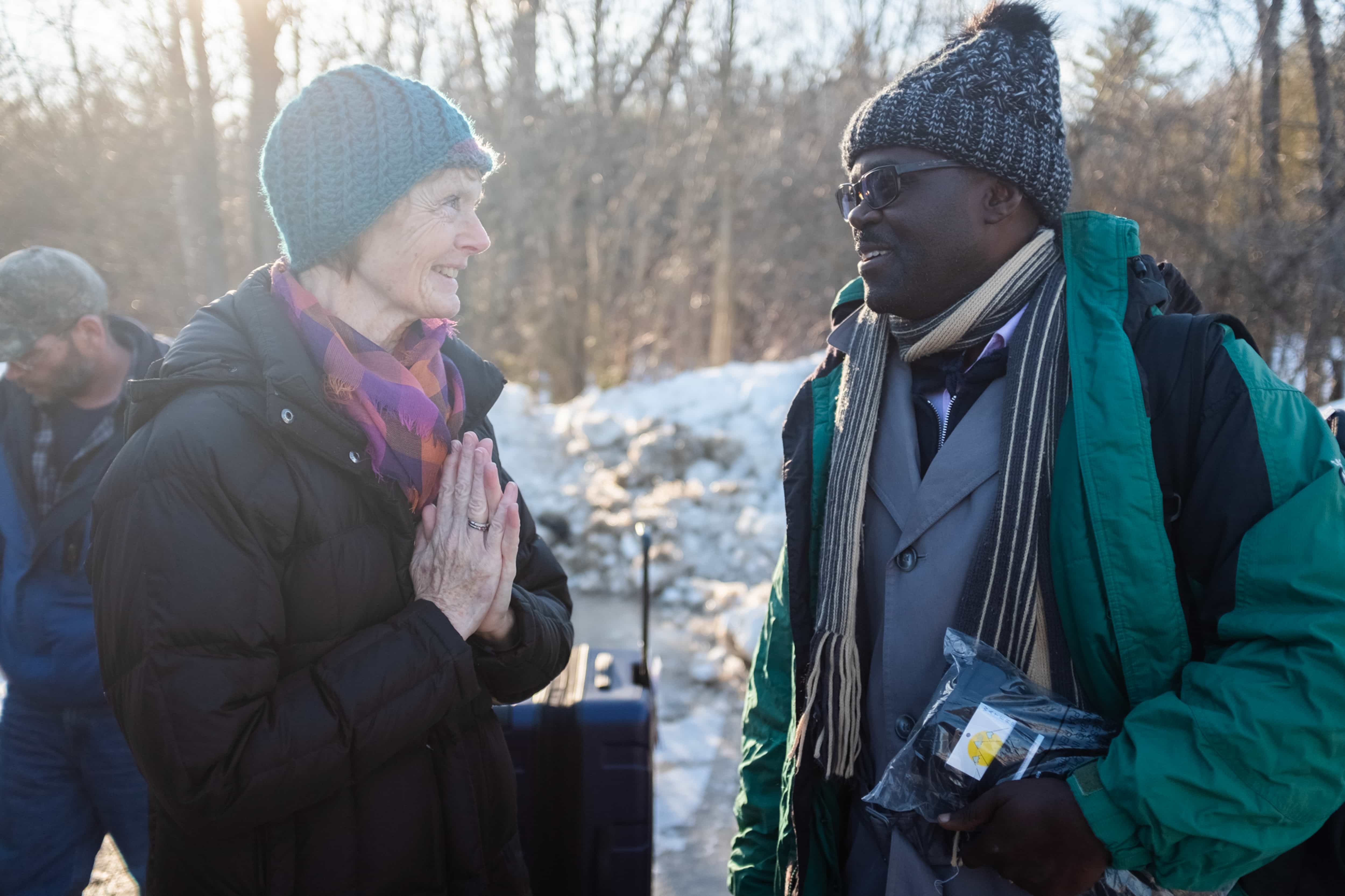 Janet McFetridge, the mayor of Champlain, NY and an immigration activist who visits Roxham Road several times a week, greets a Ugandan man as he arrives at Roxham Road and prepares to cross into Canada.
