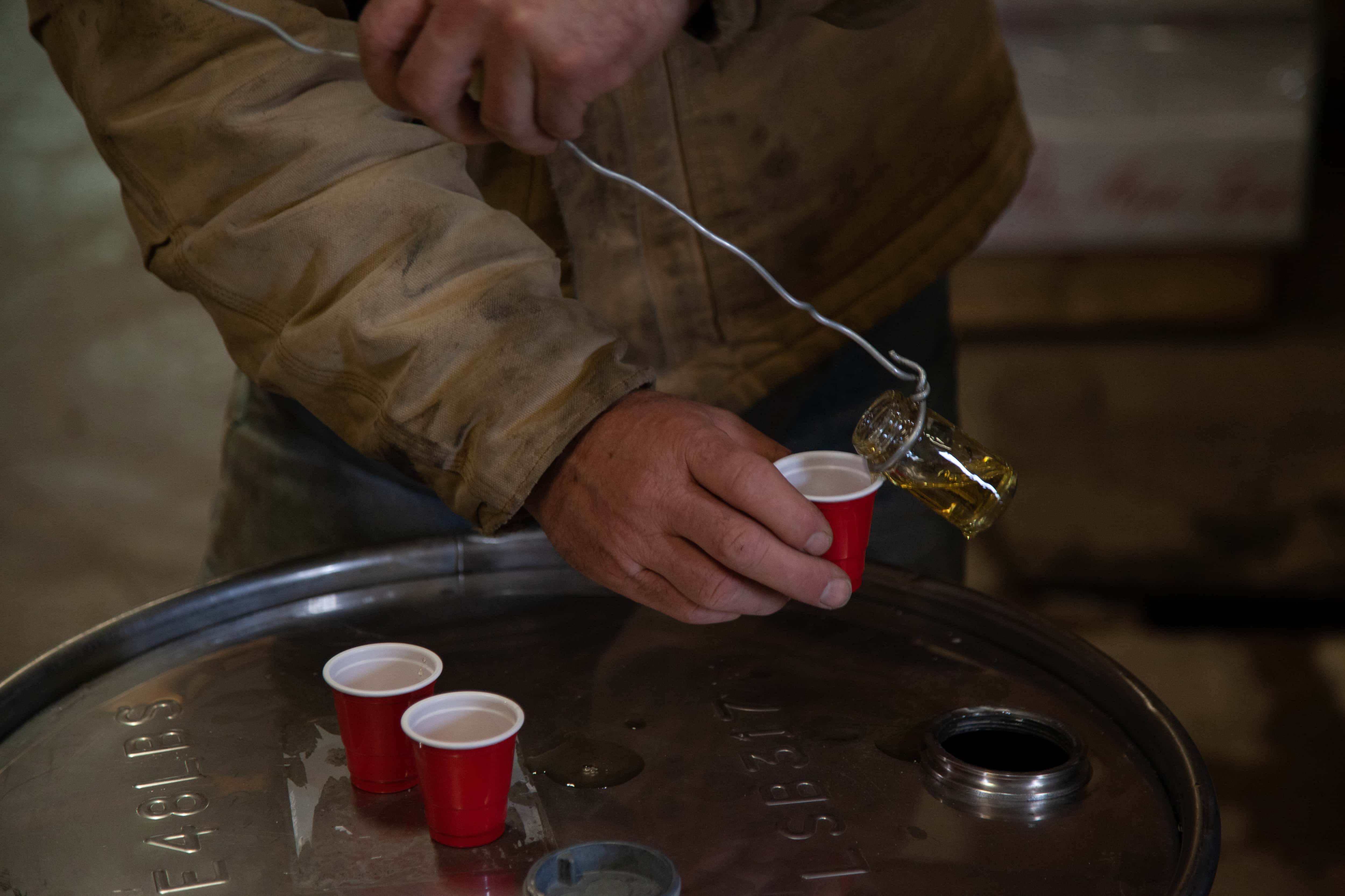 Maple farmer pouring a sample of syrup.