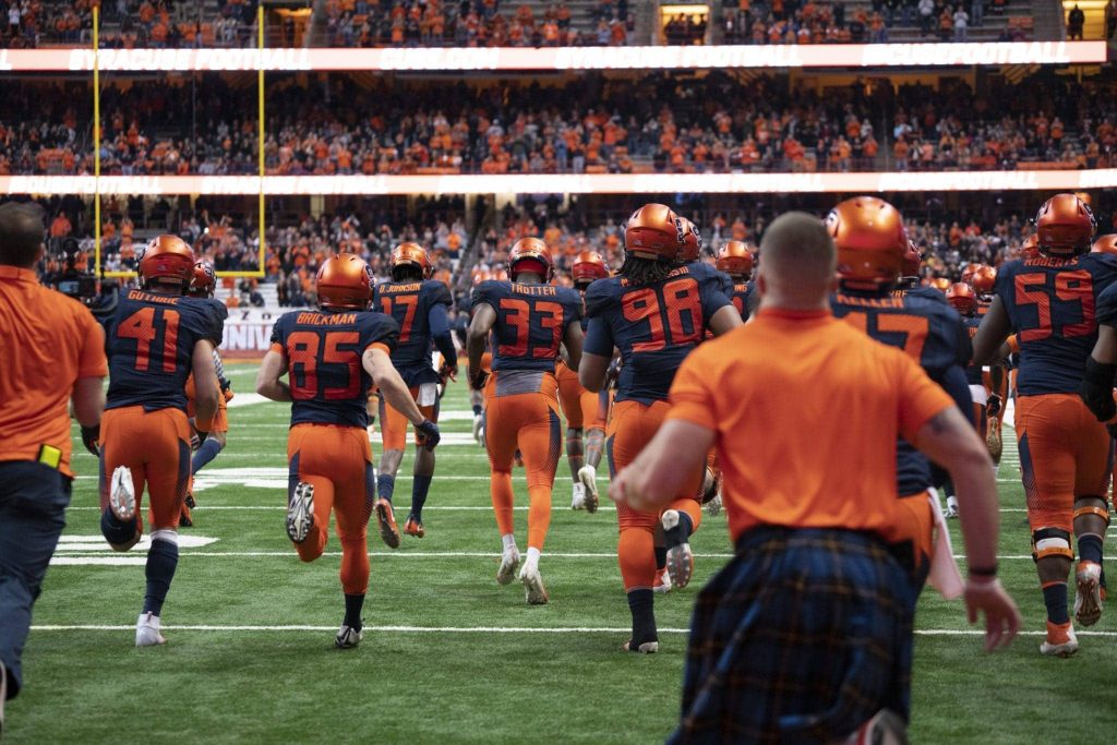 The Syracuse Orange football team runs onto field