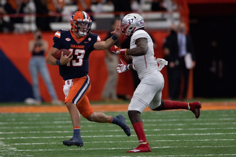 Syracuse’s Tommy DeVito (13) stiff-arms Avery Young as he runs upfield during an NCAA football game against Rutgers, Saturday, at the Carrier Dome.