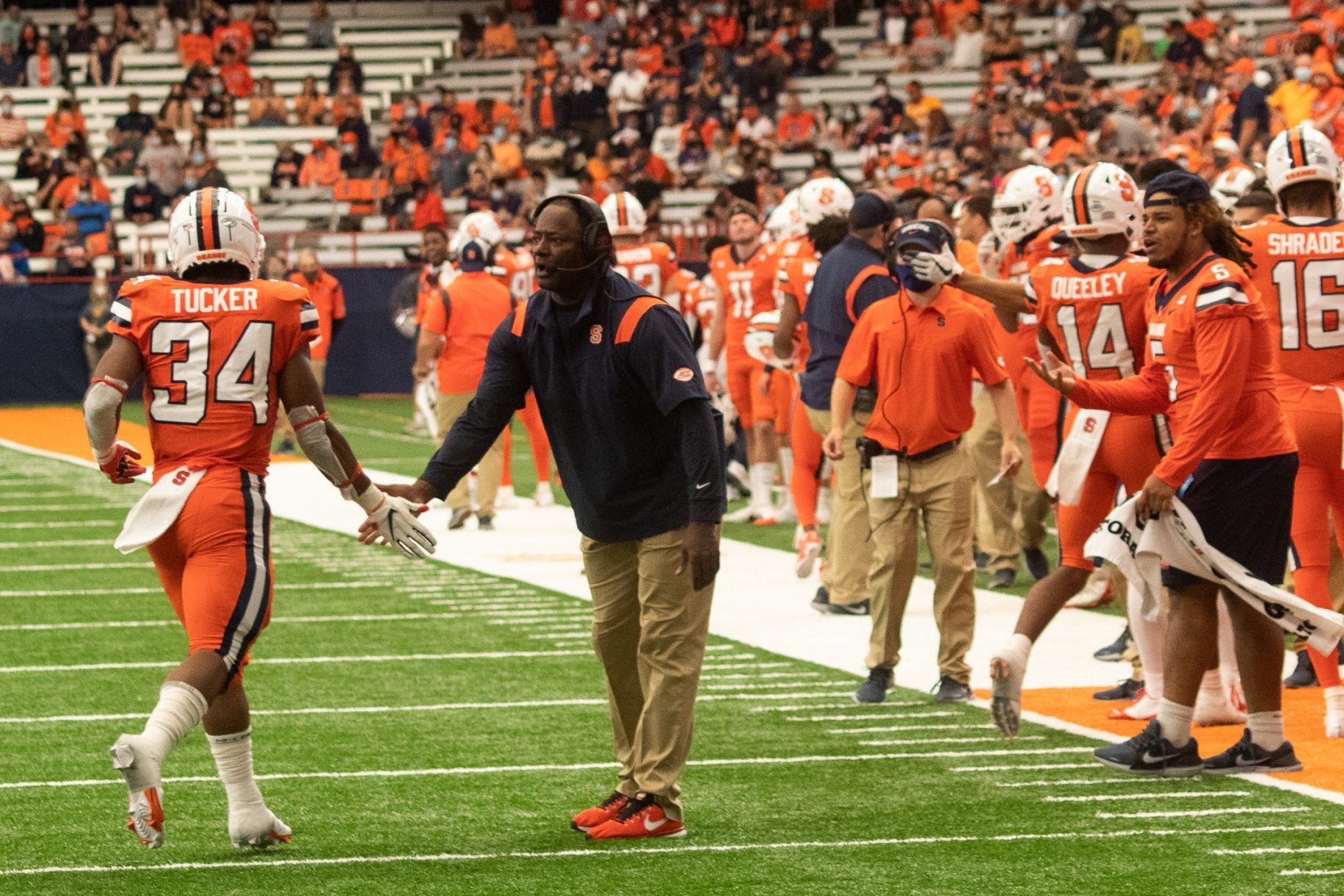 Syracuse University football coach Dino Babers high fives Sean Tucker (34) as Tucker returns to the sidelines during a NCAA football game against University of Albany, Saturday, at the Carrier Dome.