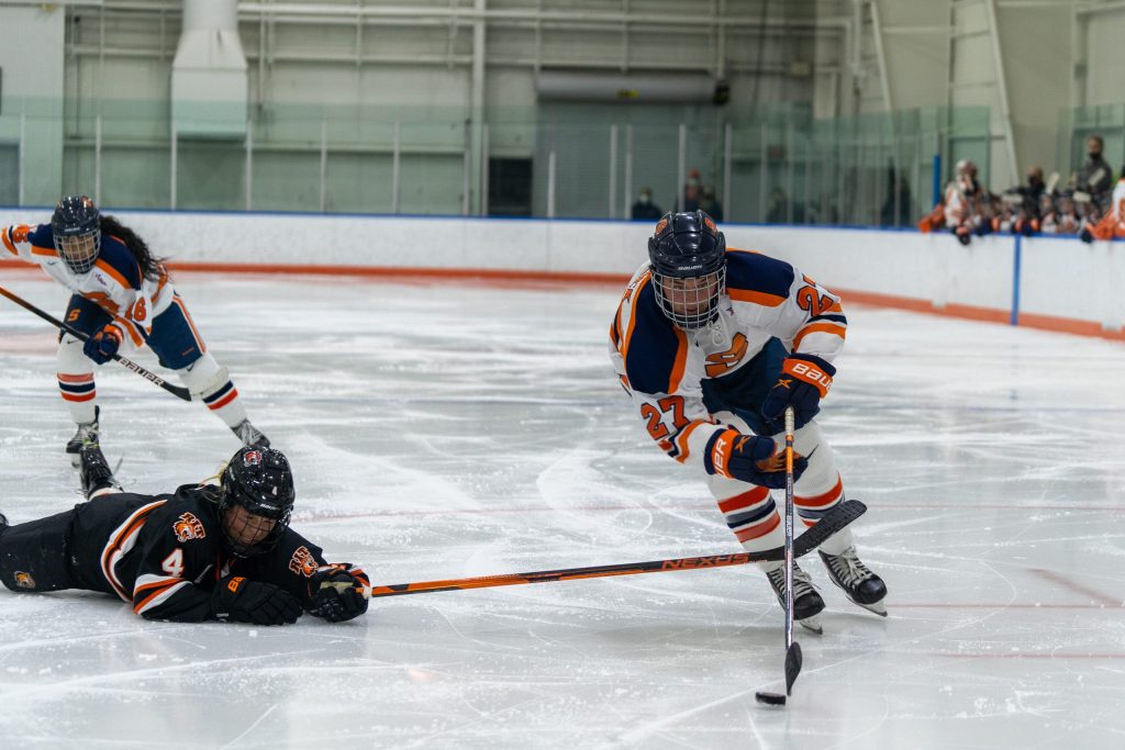 Syracuse's Victoria Klimek shields the puck from a diving RIT defender.