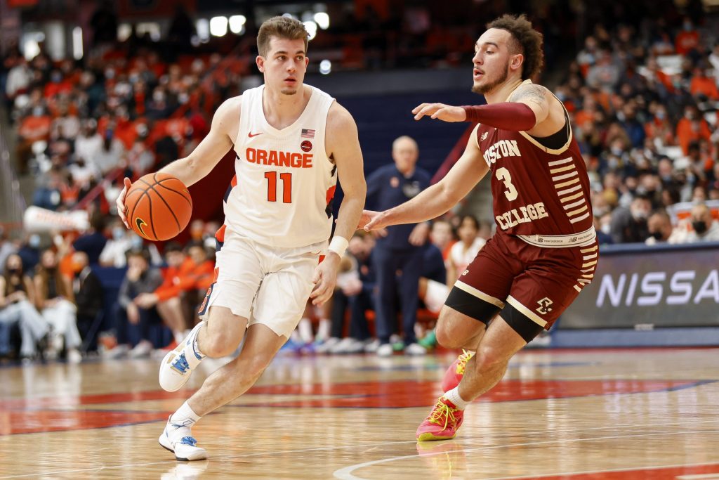 Syracuse's Joseph Girard III (11) surveys the paint and looks for a passing lane as Boston College's Jaeden Zackery defends.