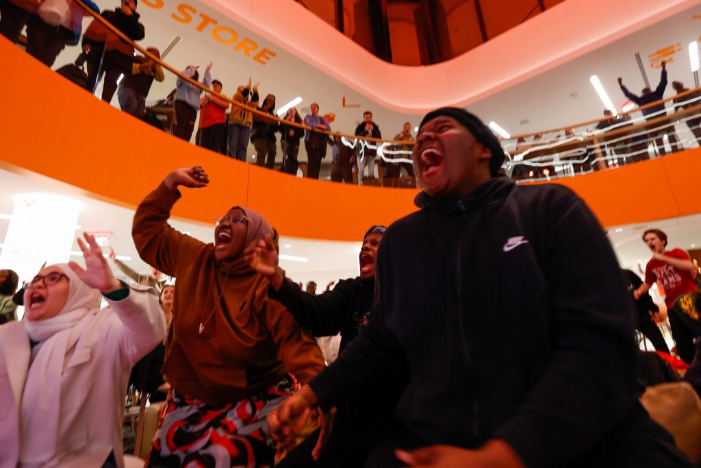 Hawa Omar (center left), and Sidle Mohamed (right), students at Syracuse, react after Syracuse scores a goal during penalty kicks at a watch party of the NCAA Men’s Soccer Championship at the Schine Student Center on December 12, 2022 in Syracuse, New York.