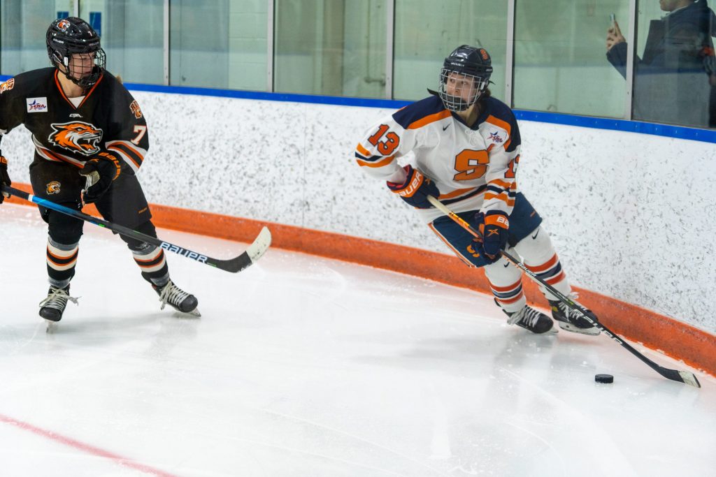 Syracuse's Abby Moloughney (13) skates past RIT's Kyla Bear (7) with possession of the puck.