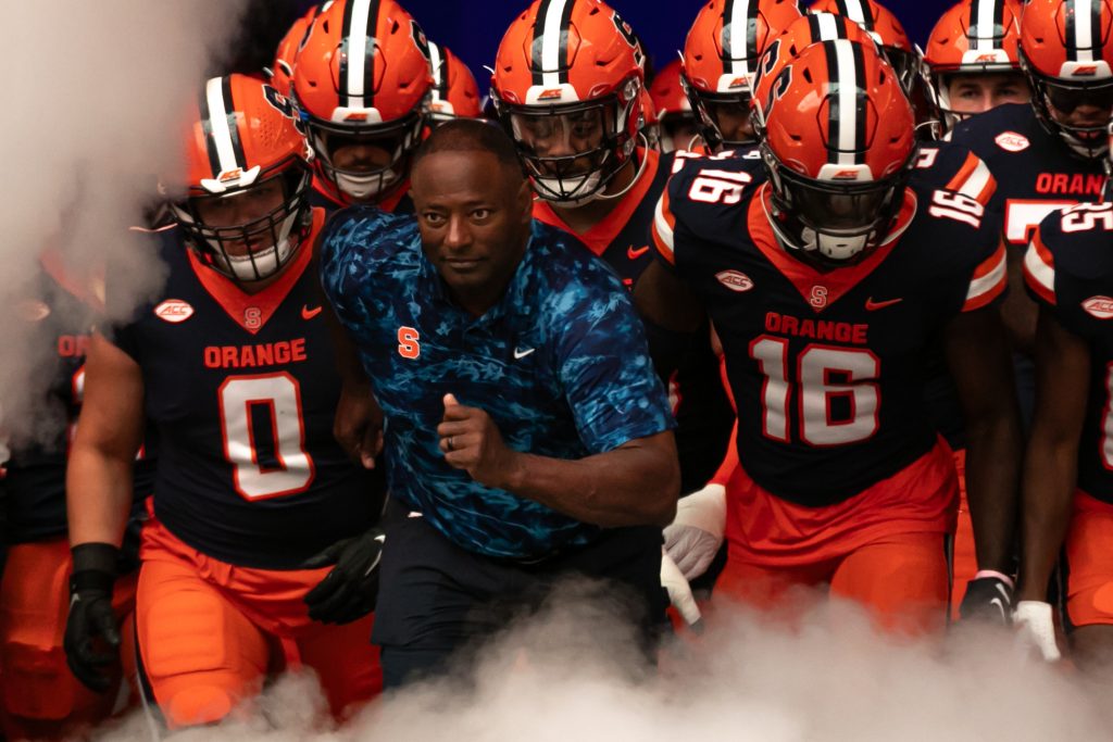 Syrcause Head Coach Dino Barbers runs out of the tunnel with the team during the season opening game against Colgate on September 2, 2023 at JMA Wireless Dome. Photo by Kayla Breen.