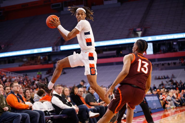 Syracuse's Chris Bell (left) leaps to keeps the ball in play before passing it off as Virginia Tech's Darius Maddox (13) watches during an ACC basketball game Wednesday at JMA Wireless Dome.