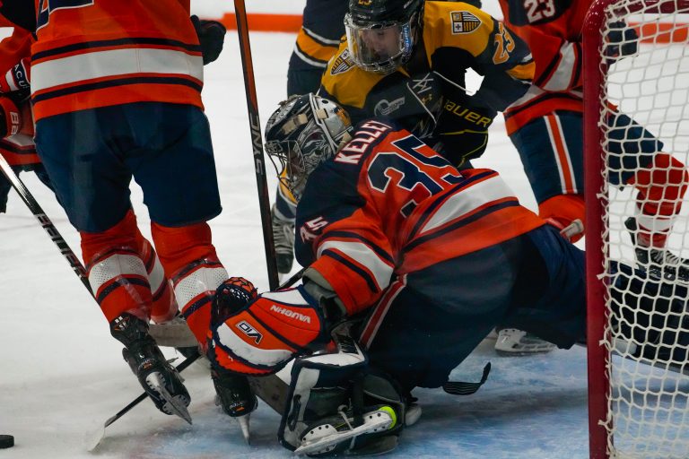 Syracuse goalie Allie Kellie (#35) drops down to guard against a goal shot from Merrimack's team.